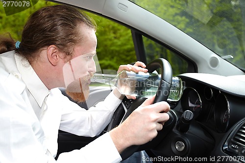 Image of Drunk man in car with a bottle alcohol