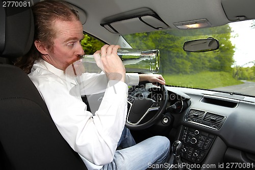 Image of Drunk man in car with a bottle alcohol