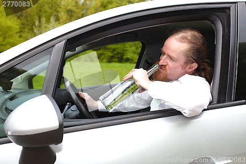 Image of Drunk man in car with a bottle alcohol