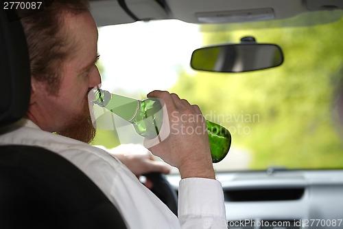 Image of Drunk man in car with a bottle beer