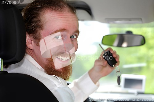 Image of driver smiling sitting in car and showing new car keys 