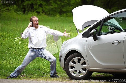 Image of Driver furious with mobile phone a broken car by the road 