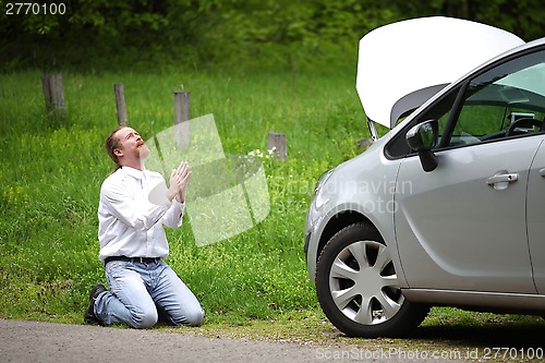 Image of Funny driver praying a broken car by the road  