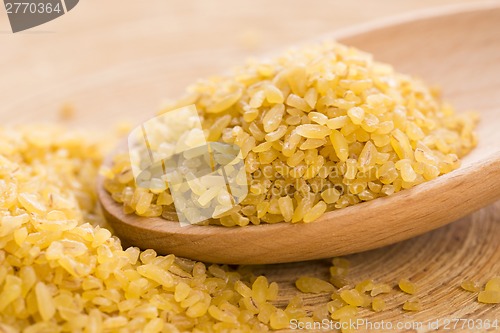 Image of bulgur wheat in wooden spoon