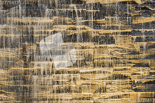 Image of Falling water stream against stonework rough texture