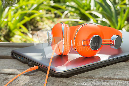 Image of Bright coloured orange headphones and mobile computer