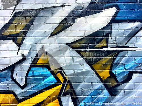 Image of Blue and yellow graffiti detail on a brick wall
