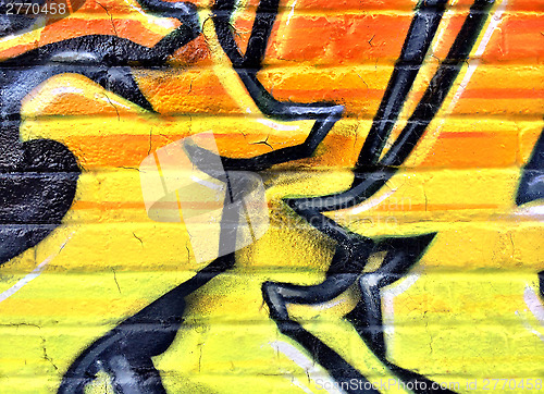 Image of Black and yellow graffiti detail on a brick wall