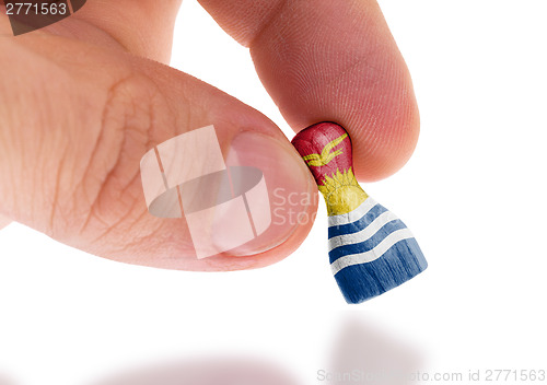 Image of Hand holding wooden pawn, flag painting, selective focus