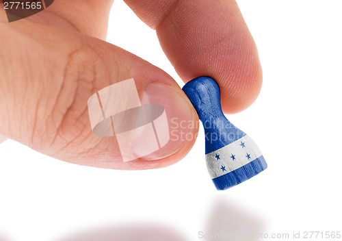 Image of Hand holding wooden pawn, flag painting, selective focus