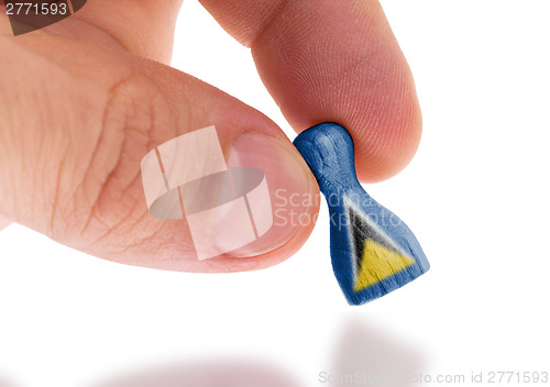 Image of Hand holding wooden pawn, flag painting, selective focus