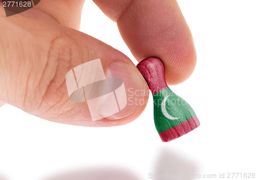 Image of Hand holding wooden pawn, flag painting, selective focus