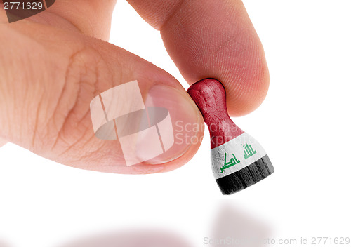 Image of Hand holding wooden pawn, flag painting, selective focus