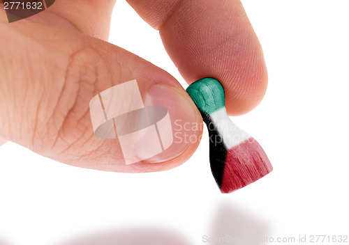 Image of Hand holding wooden pawn, flag painting, selective focus