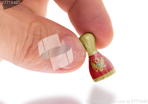 Image of Hand holding wooden pawn, flag painting, selective focus