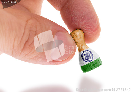 Image of Hand holding wooden pawn, flag painting, selective focus