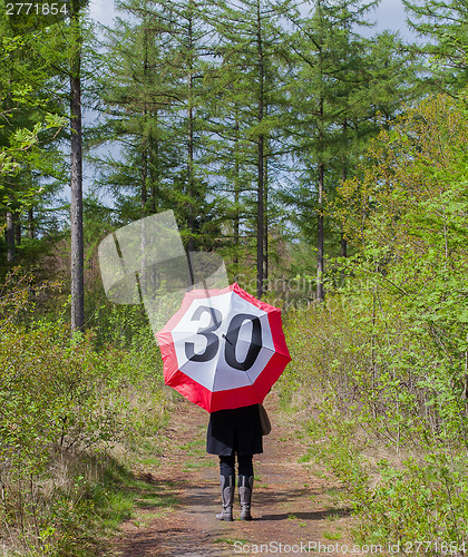 Image of Woman in the forrest with a traffic sign umbrella