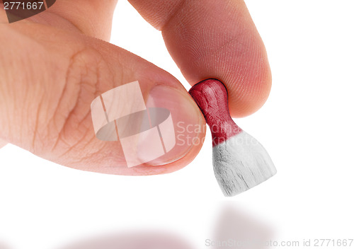 Image of Hand holding wooden pawn, flag painting, selective focus