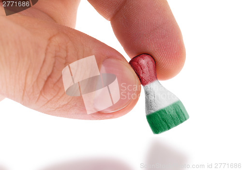 Image of Hand holding wooden pawn, flag painting, selective focus