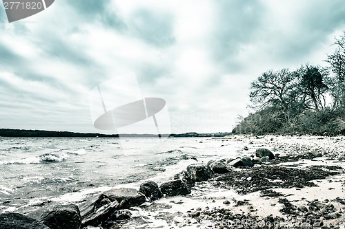 Image of Waves coming in at big black rocks on the shore on a cold day