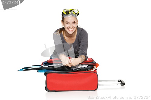 Image of Happy female packing her suitcase