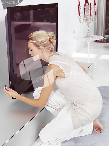 Image of Beautiful blond woman sitting near tv