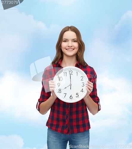 Image of young woman in casual clothes with wall clock