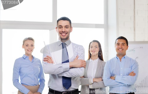 Image of smiling businessman in office with team on back