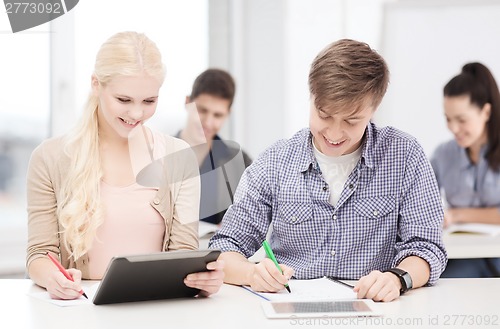 Image of two smiling students with tablet pc and notebooks