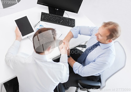 Image of businessmen shaking hands in office