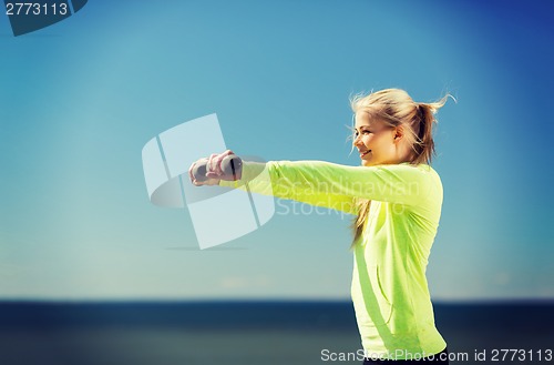 Image of sporty woman with light dumbbells outdoors