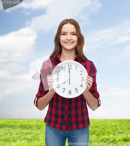 Image of young woman in casual clothes with wall clock