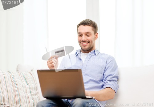 Image of smiling man working with laptop and credit card