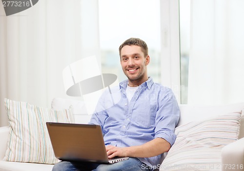Image of smiling man working with laptop at home