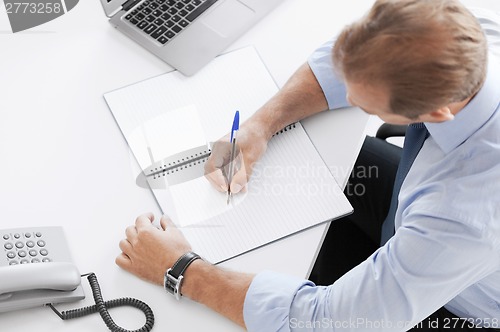 Image of businessman writing in notebook
