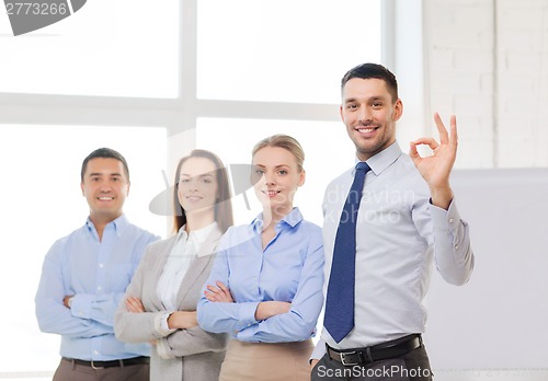 Image of smiling businessman showing ok-sign in office