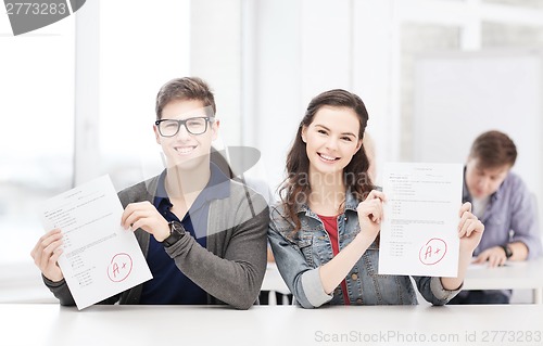 Image of two teenagers holding test or exam with grade A