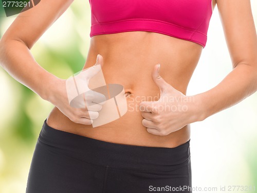 Image of close up of female abs and hands showing thumbs up