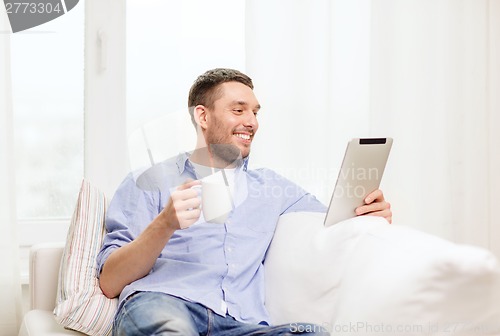 Image of smiling man working with tablet pc at home