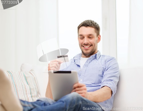 Image of smiling man working with tablet pc at home