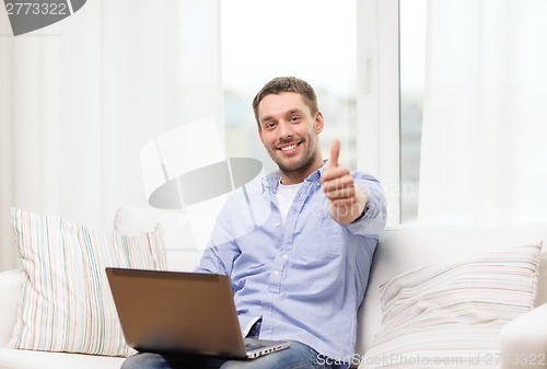 Image of smiling man working with laptop at home