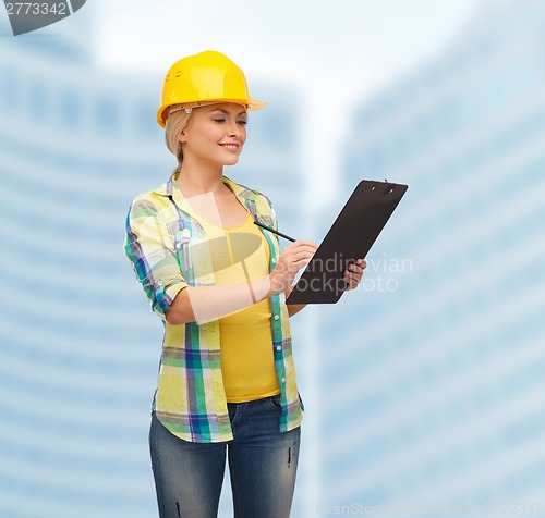 Image of smiling woman in helmet with clipboard