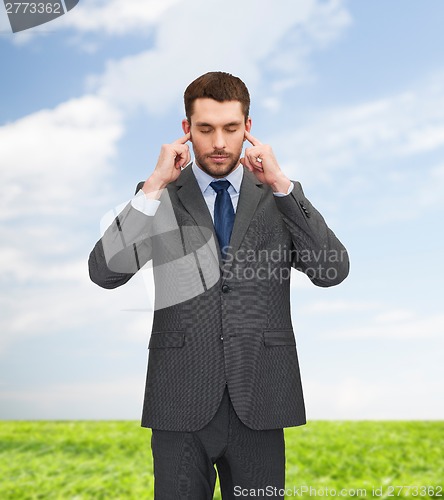 Image of annoyed businessman covering ears with his hands