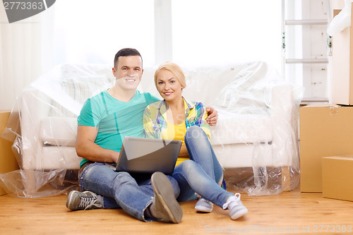 Image of couple with laptop sitting on floor in new house