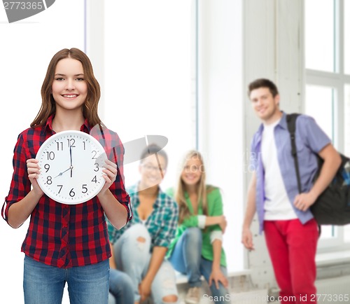 Image of young woman in casual clothes with wall clock