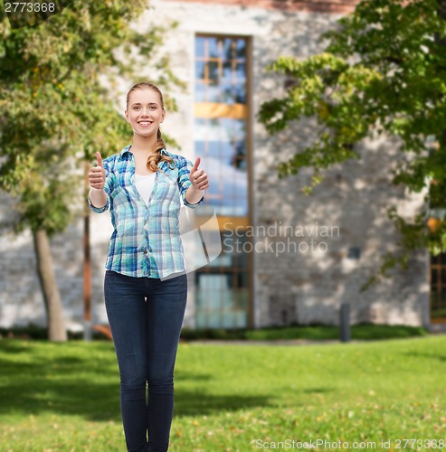 Image of young woman in casual clothes showing thumbs up