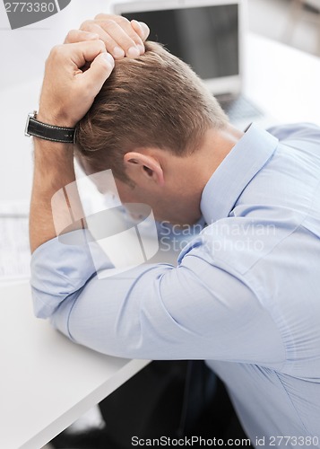 Image of stressed businessman with papers at work