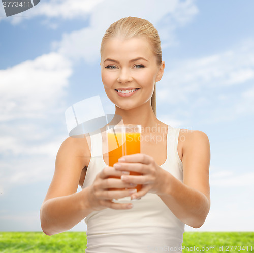 Image of smiling woman holding glass of orange juice