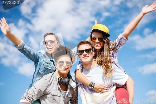 Image of smiling teenagers in sunglasses having fun outside