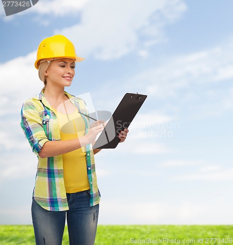 Image of smiling woman in helmet with clipboard